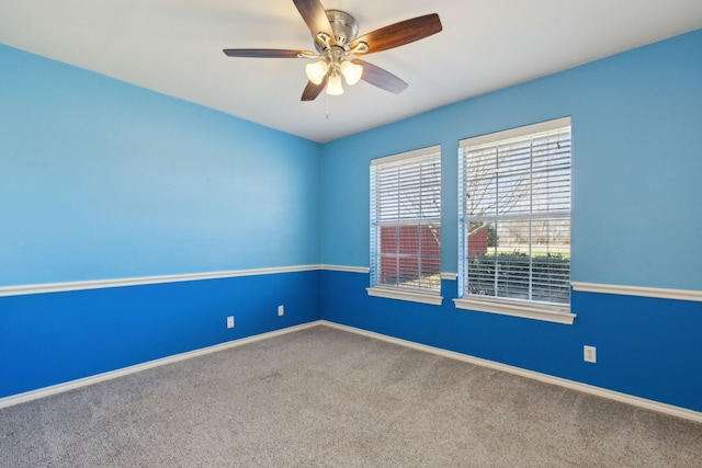 carpeted empty room featuring baseboards and a ceiling fan