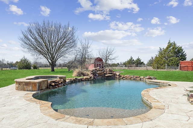 outdoor pool with an in ground hot tub, a lawn, fence, and a patio area