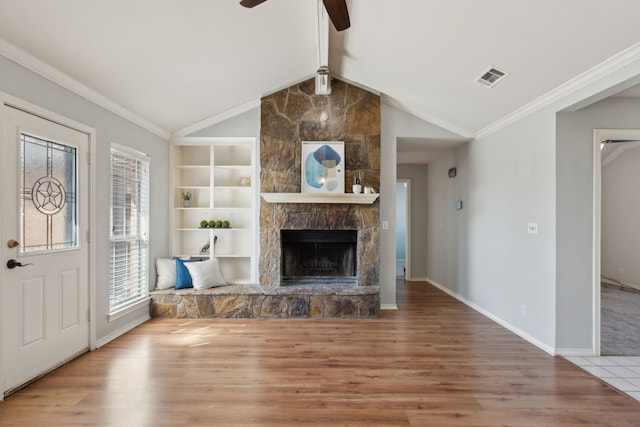 unfurnished living room featuring visible vents, lofted ceiling with beams, a fireplace, ornamental molding, and light wood-style floors