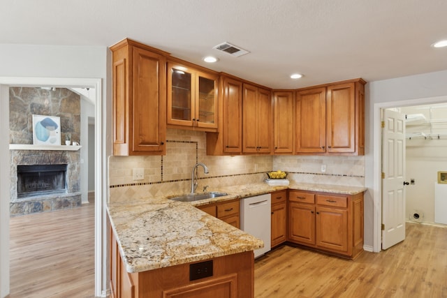 kitchen with white dishwasher, visible vents, light wood finished floors, and a sink