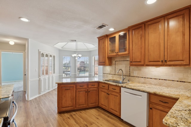 kitchen featuring dishwasher, brown cabinets, a peninsula, stove, and a sink