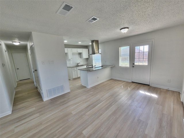 kitchen with visible vents, a sink, and wall chimney exhaust hood