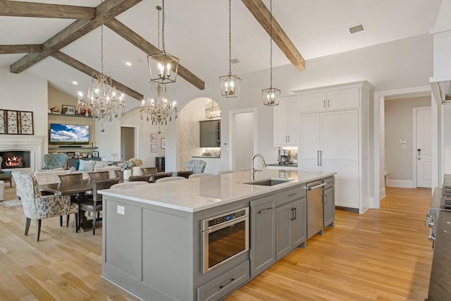 kitchen with appliances with stainless steel finishes, open floor plan, gray cabinets, high vaulted ceiling, and a sink