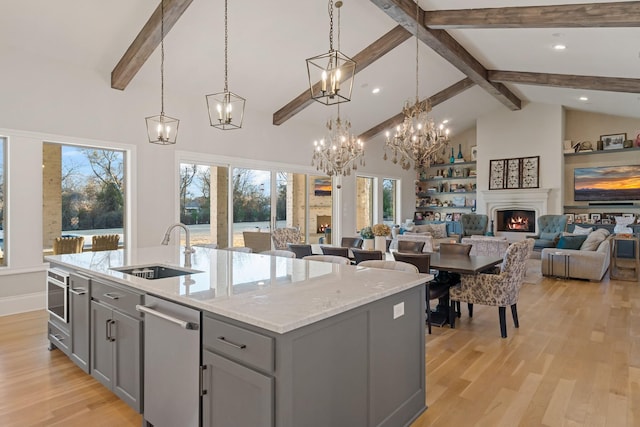 kitchen featuring a warm lit fireplace, high vaulted ceiling, a sink, open floor plan, and gray cabinets