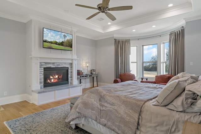 bedroom with ornamental molding, light wood finished floors, a raised ceiling, and baseboards