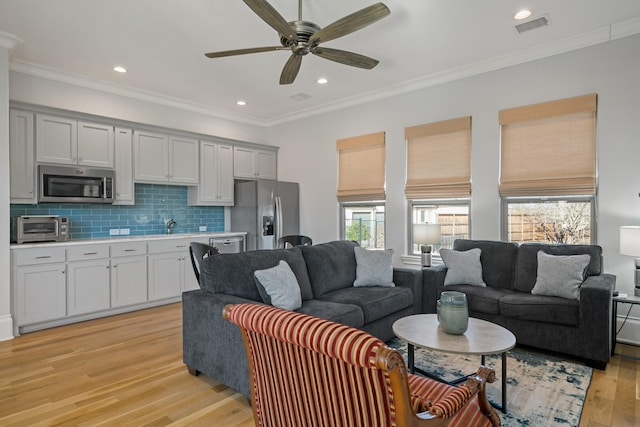 living area featuring ornamental molding, a toaster, visible vents, and light wood-style flooring