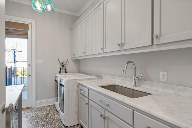 clothes washing area featuring crown molding, cabinet space, a sink, independent washer and dryer, and baseboards