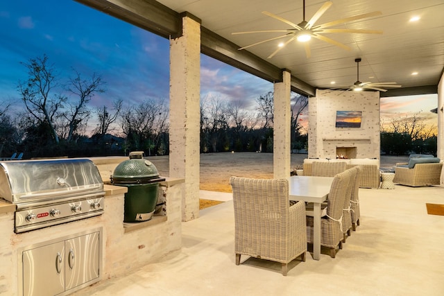 patio terrace at dusk with ceiling fan, outdoor dining space, and area for grilling