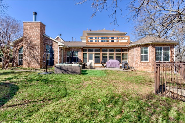 rear view of property with a yard, brick siding, a chimney, and a patio area