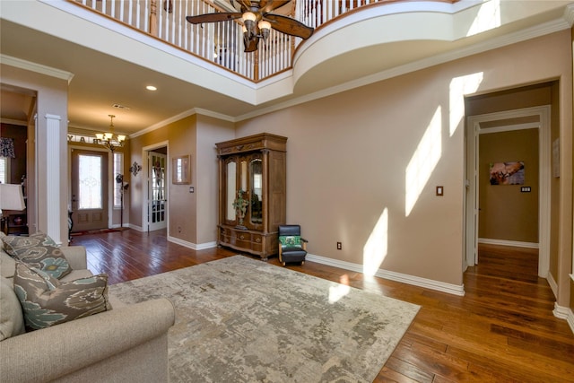 living room featuring ornamental molding, wood-type flooring, a high ceiling, and baseboards