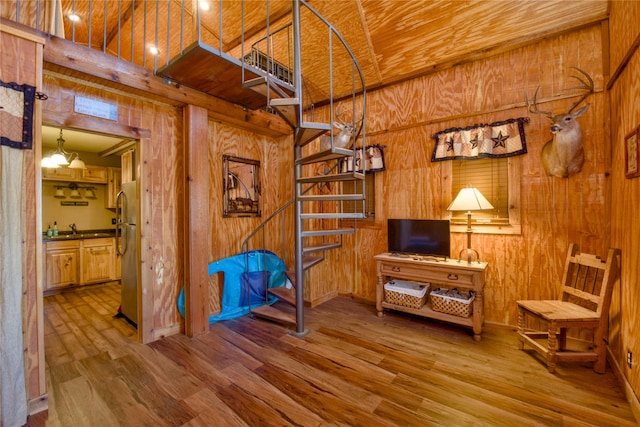 sitting room with wood walls, stairway, and wood finished floors