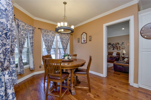 dining room featuring a chandelier, ornamental molding, baseboards, and hardwood / wood-style flooring