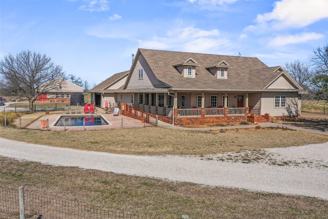 view of front facade with a porch, fence, roof with shingles, a fenced in pool, and a front yard