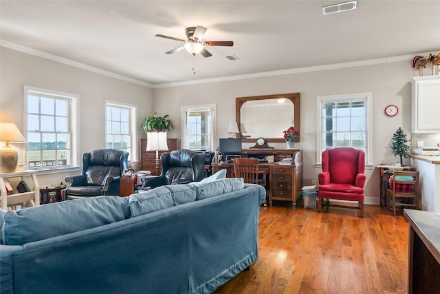 living area with light wood-type flooring, ceiling fan, visible vents, and crown molding