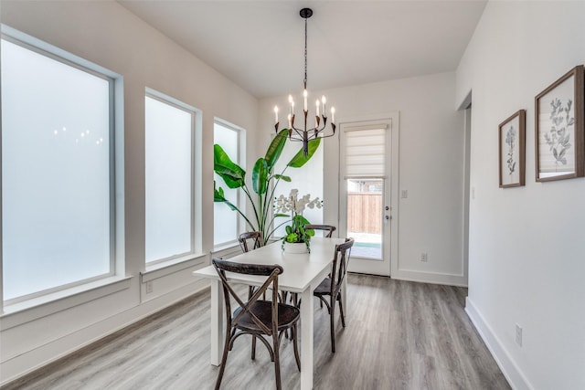 dining area with baseboards, light wood finished floors, and an inviting chandelier