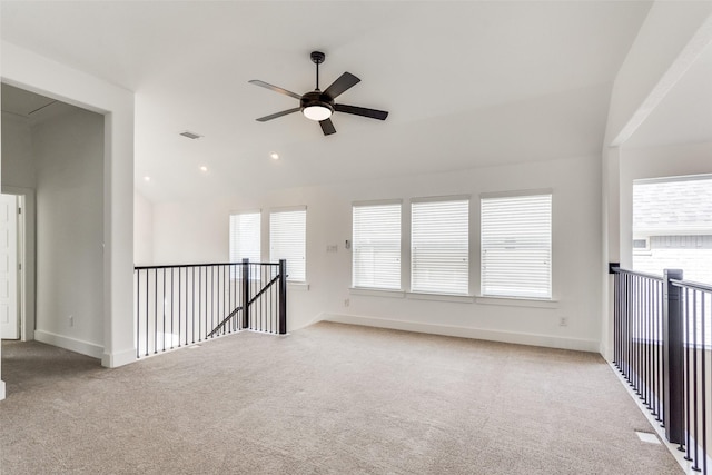 empty room featuring lofted ceiling, carpet, visible vents, and baseboards