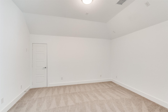 unfurnished room featuring lofted ceiling, baseboards, visible vents, and light colored carpet