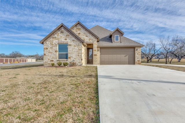 french country inspired facade featuring a garage, driveway, a shingled roof, and a front yard