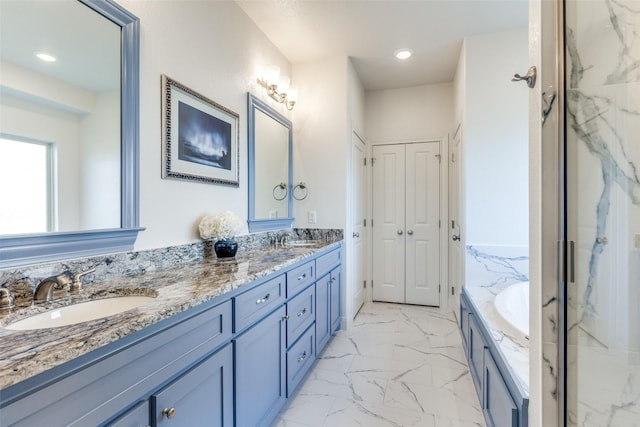 full bath featuring double vanity, marble finish floor, a sink, and a bath