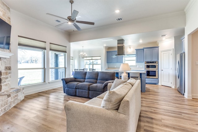 living room featuring light wood-style floors, visible vents, crown molding, and a fireplace