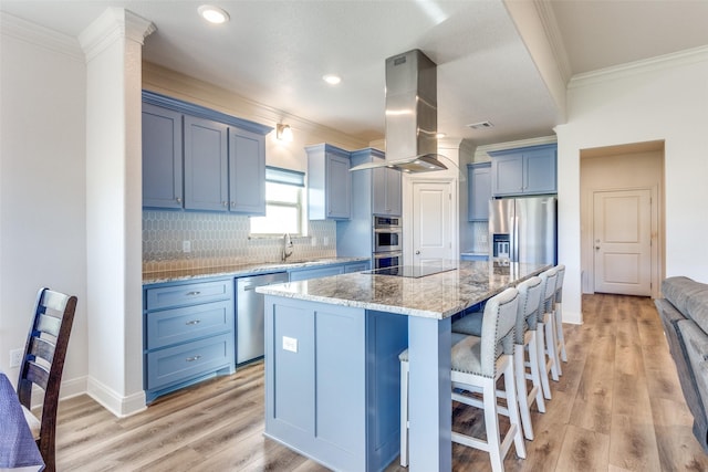 kitchen with a kitchen island, appliances with stainless steel finishes, light stone countertops, island exhaust hood, and blue cabinetry