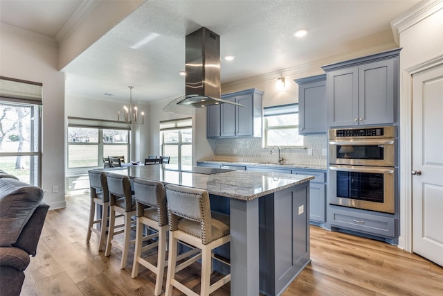 648 Half Moon Way, Runaway Bay, TX 76426 - kitchen with island range hood, double oven, a sink, light stone countertops, and a kitchen island