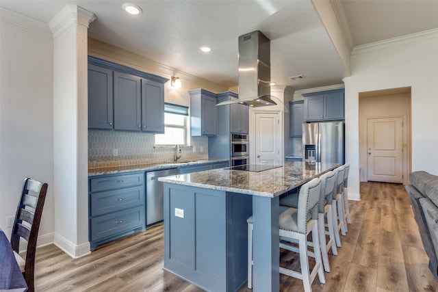 648 Half Moon Way, Runaway Bay, TX 76426 - kitchen with island exhaust hood, crown molding, stainless steel appliances, stone countertops, and blue cabinets