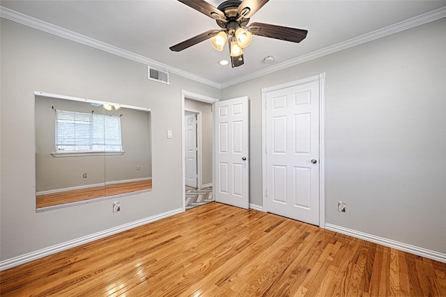 unfurnished bedroom with light wood finished floors, baseboards, visible vents, and crown molding