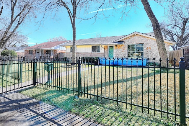 view of front of home featuring stone siding, brick siding, a fenced front yard, and a front lawn