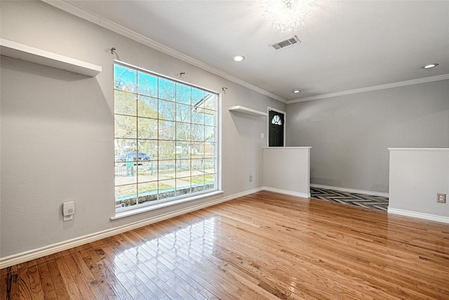 unfurnished room with baseboards, visible vents, crown molding, and hardwood / wood-style floors