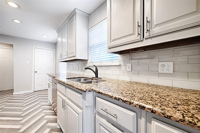 kitchen featuring recessed lighting, decorative backsplash, a sink, light stone countertops, and dishwasher