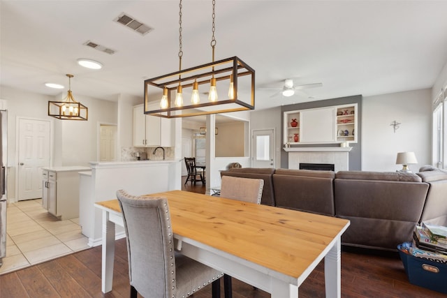 dining space featuring a tile fireplace, visible vents, and hardwood / wood-style flooring