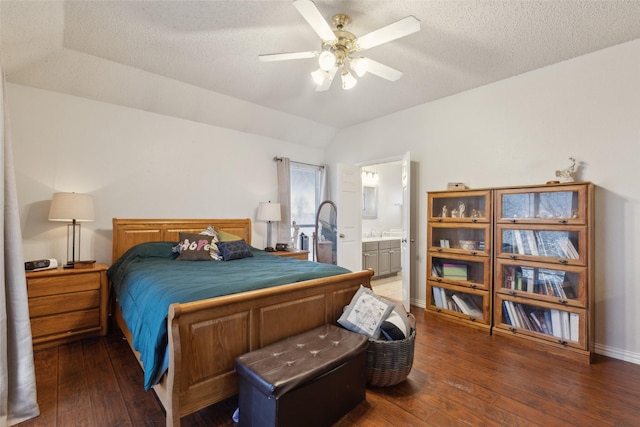 bedroom with lofted ceiling, a textured ceiling, baseboards, wood-type flooring, and ensuite bath