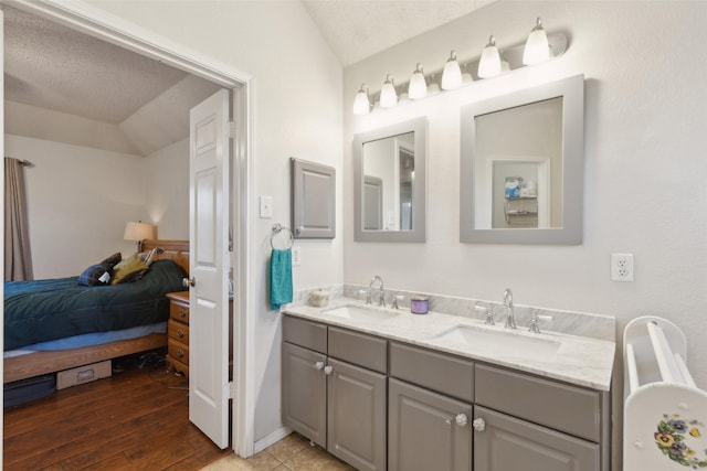 ensuite bathroom with vaulted ceiling, double vanity, ensuite bath, and a sink