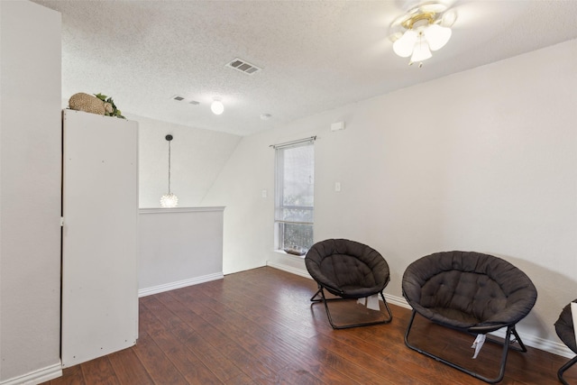 sitting room featuring baseboards, visible vents, a textured ceiling, and hardwood / wood-style floors