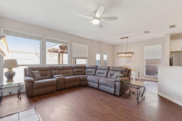 living area featuring a wealth of natural light, visible vents, and wood finished floors