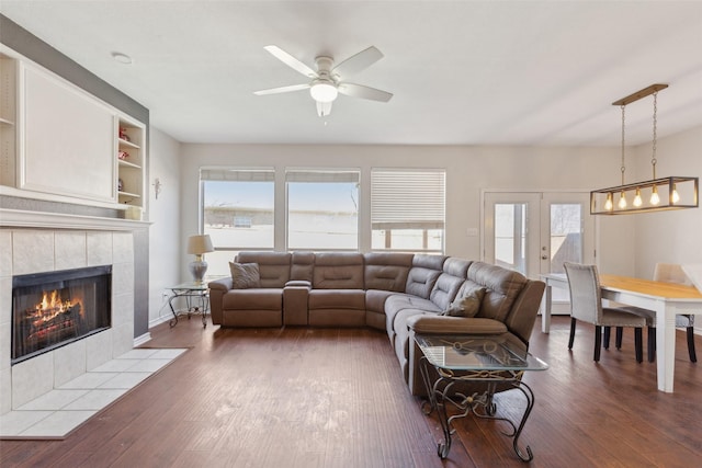 living room with ceiling fan, french doors, a tile fireplace, and wood finished floors