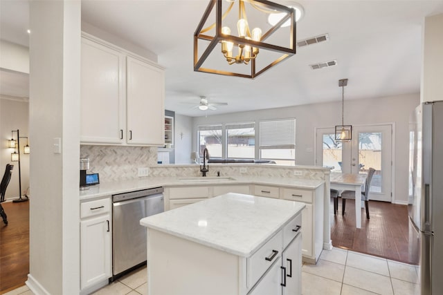 kitchen featuring a peninsula, appliances with stainless steel finishes, a sink, and visible vents