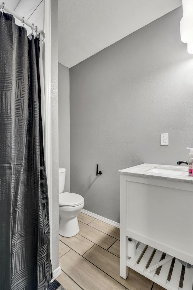 full bathroom featuring toilet, a shower with curtain, baseboards, and vanity