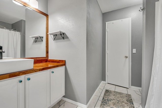 full bath with marble finish floor, baseboards, and vanity