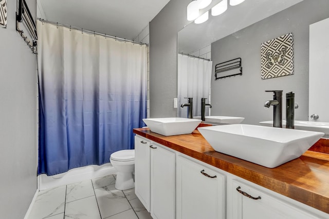 bathroom with double vanity, marble finish floor, a shower with curtain, and a sink