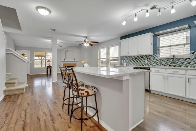 kitchen featuring tasteful backsplash, visible vents, light wood-style floors, and a breakfast bar area