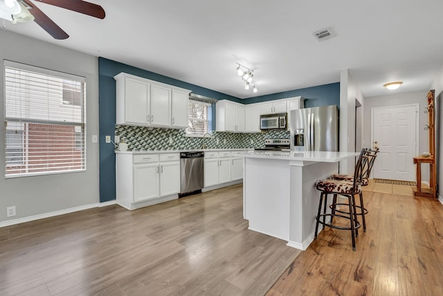 kitchen featuring stainless steel appliances, backsplash, visible vents, and white cabinets