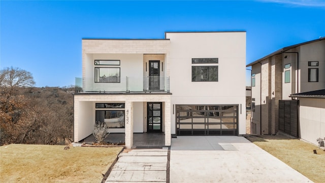 contemporary home with concrete driveway, an attached garage, a balcony, and stucco siding