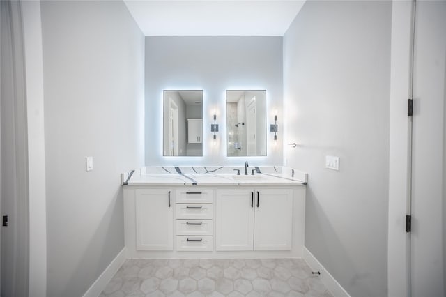 bathroom with double vanity, baseboards, and a sink