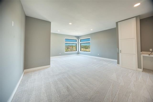 empty room featuring baseboards, recessed lighting, and light colored carpet