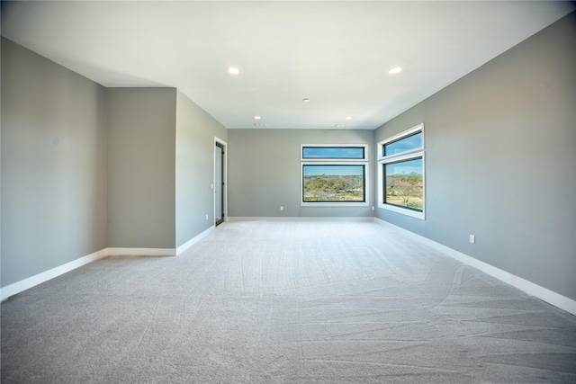 spare room featuring recessed lighting, light colored carpet, and baseboards