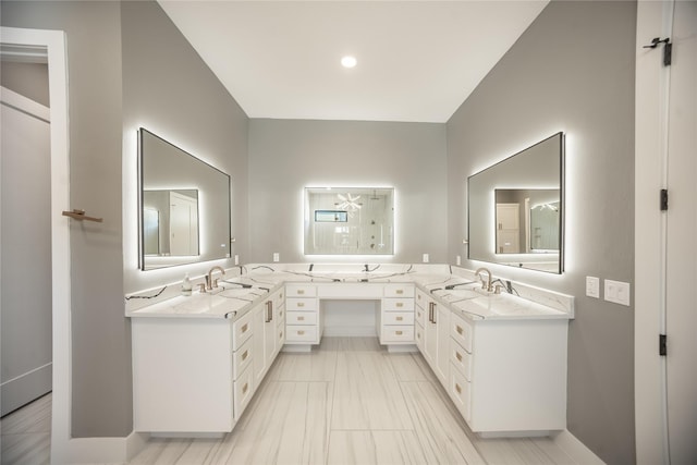 bathroom with double vanity, a shower, and a sink