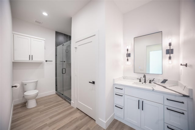 bathroom with toilet, wood finished floors, vanity, visible vents, and a shower stall