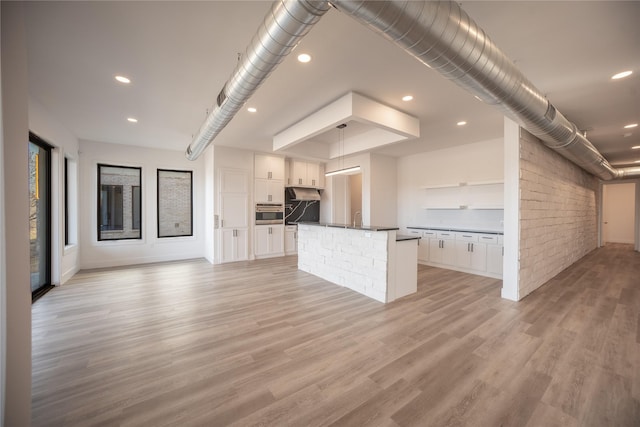 kitchen with dark countertops, light wood-style flooring, open floor plan, white cabinets, and a sink